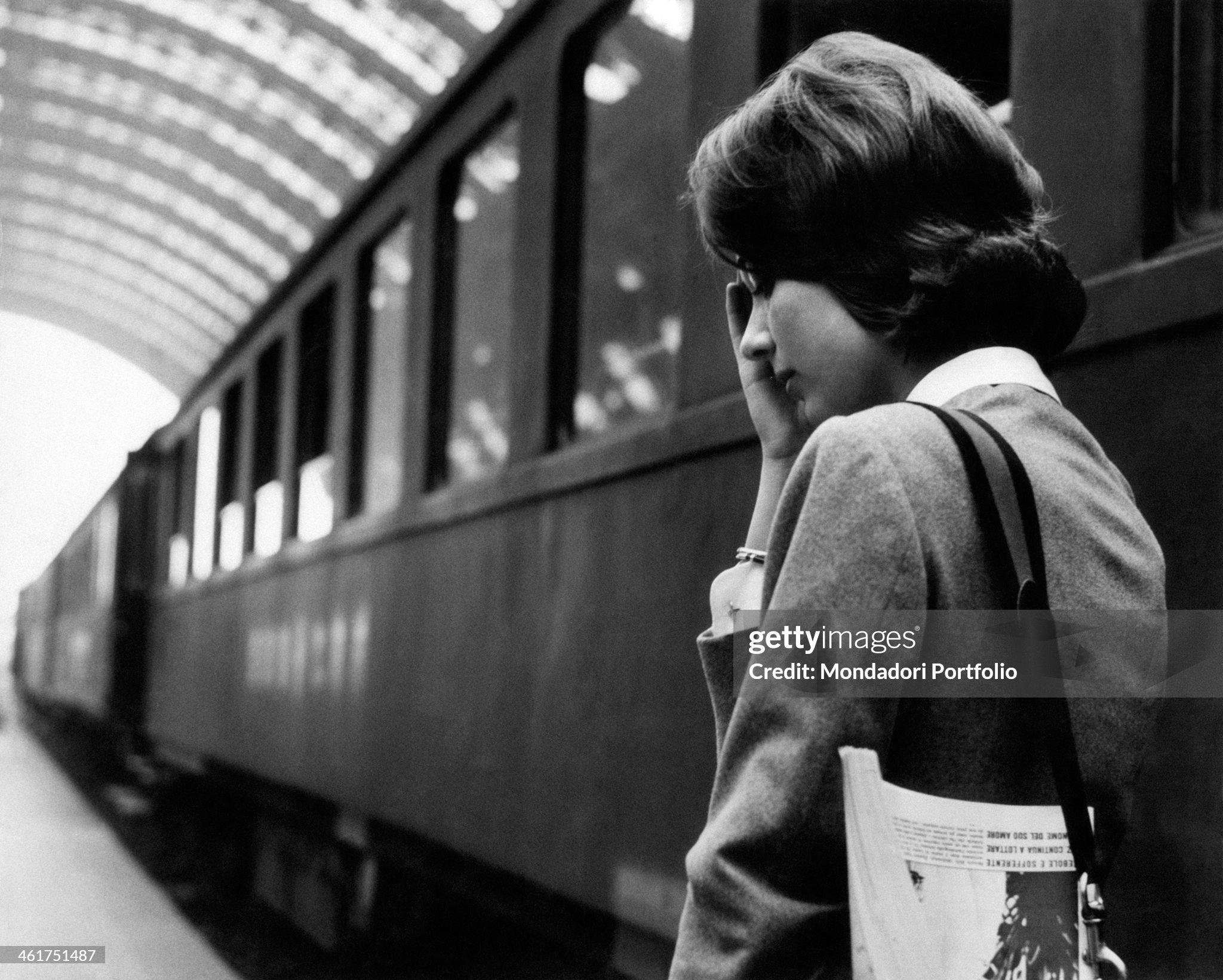 A young woman looking thoughtful beside a train at Milan Central Station in April 1961. 