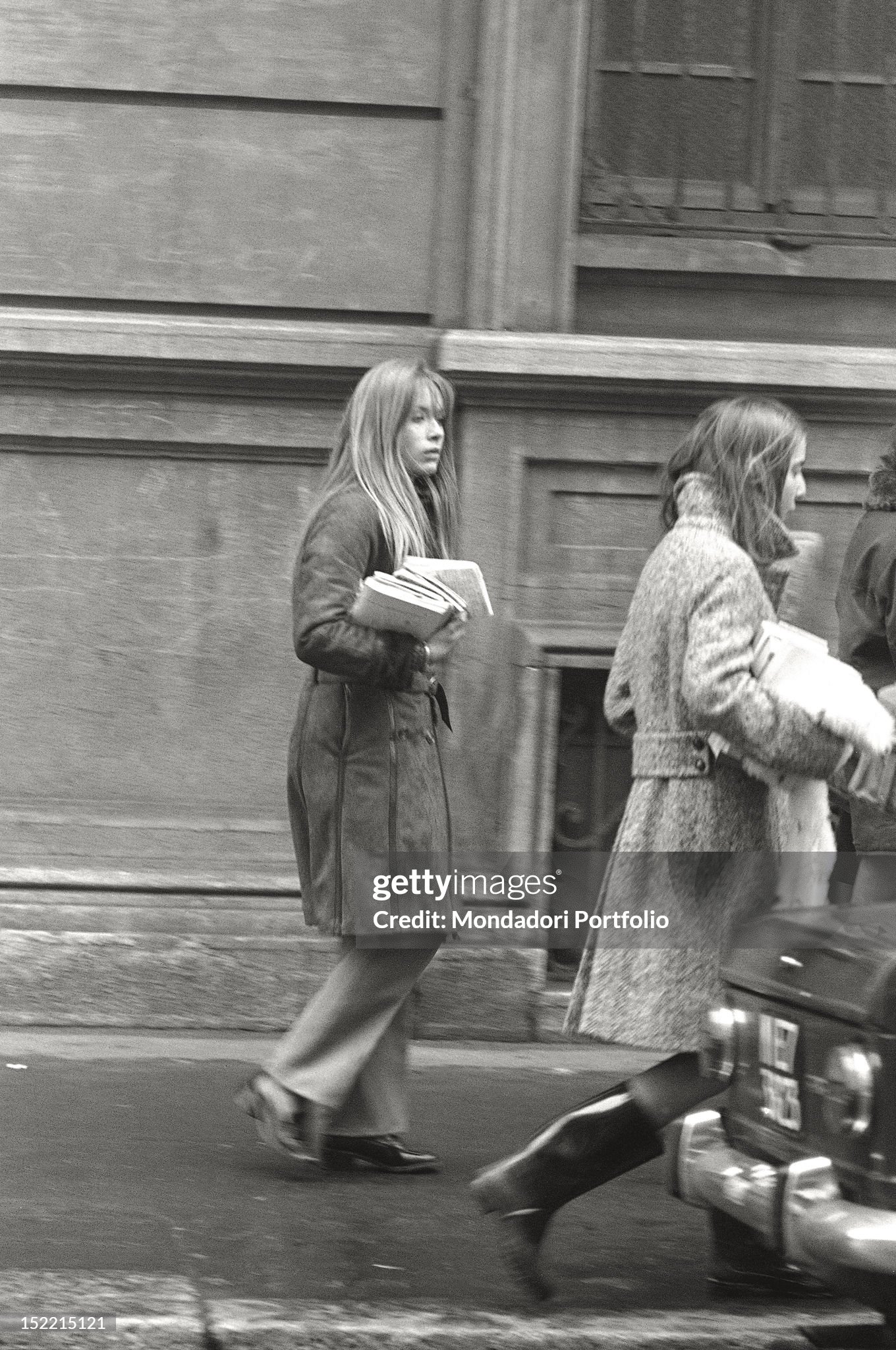 Two girls on the street are carrying books in their arms in Milan in 1969. 