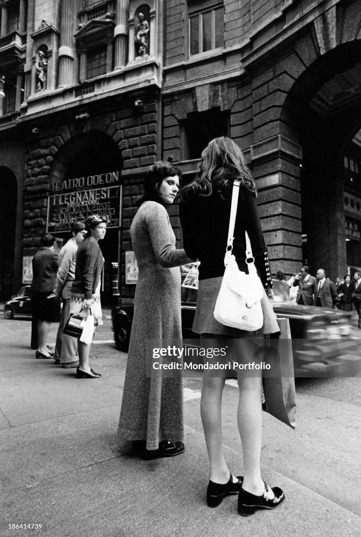Two girls seen from the back in Corso Vittorio Emanuele in Milan in 1970: one of the two is wearing a maxi-skirt, the other is wearing a mini-skirt. 