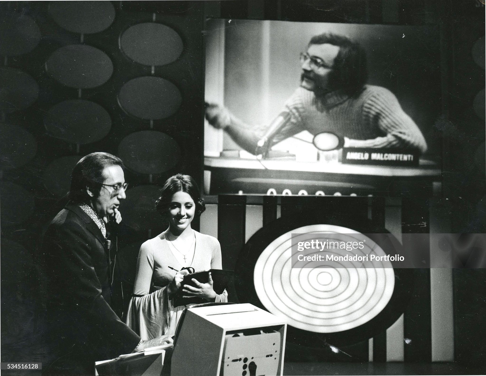 Mike Bongiorno beside Sabina Ciuffini in the TV quiz show 'Rischiatutto' in Milan in 1970. On the monitor, the competitor Angelo Malcontenti. 