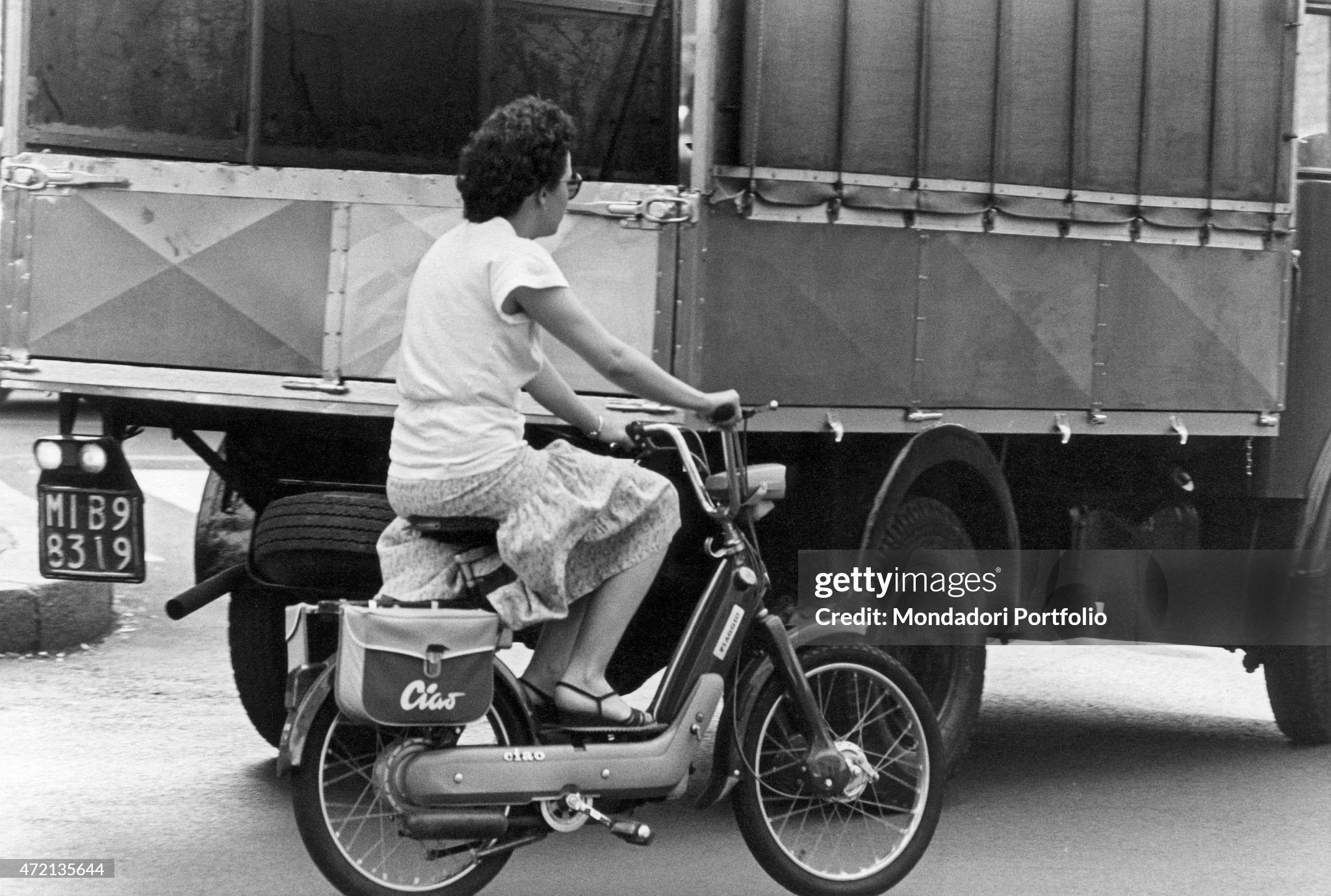 A girl riding a Piaggio Ciao moped in Milan in 1970s. 