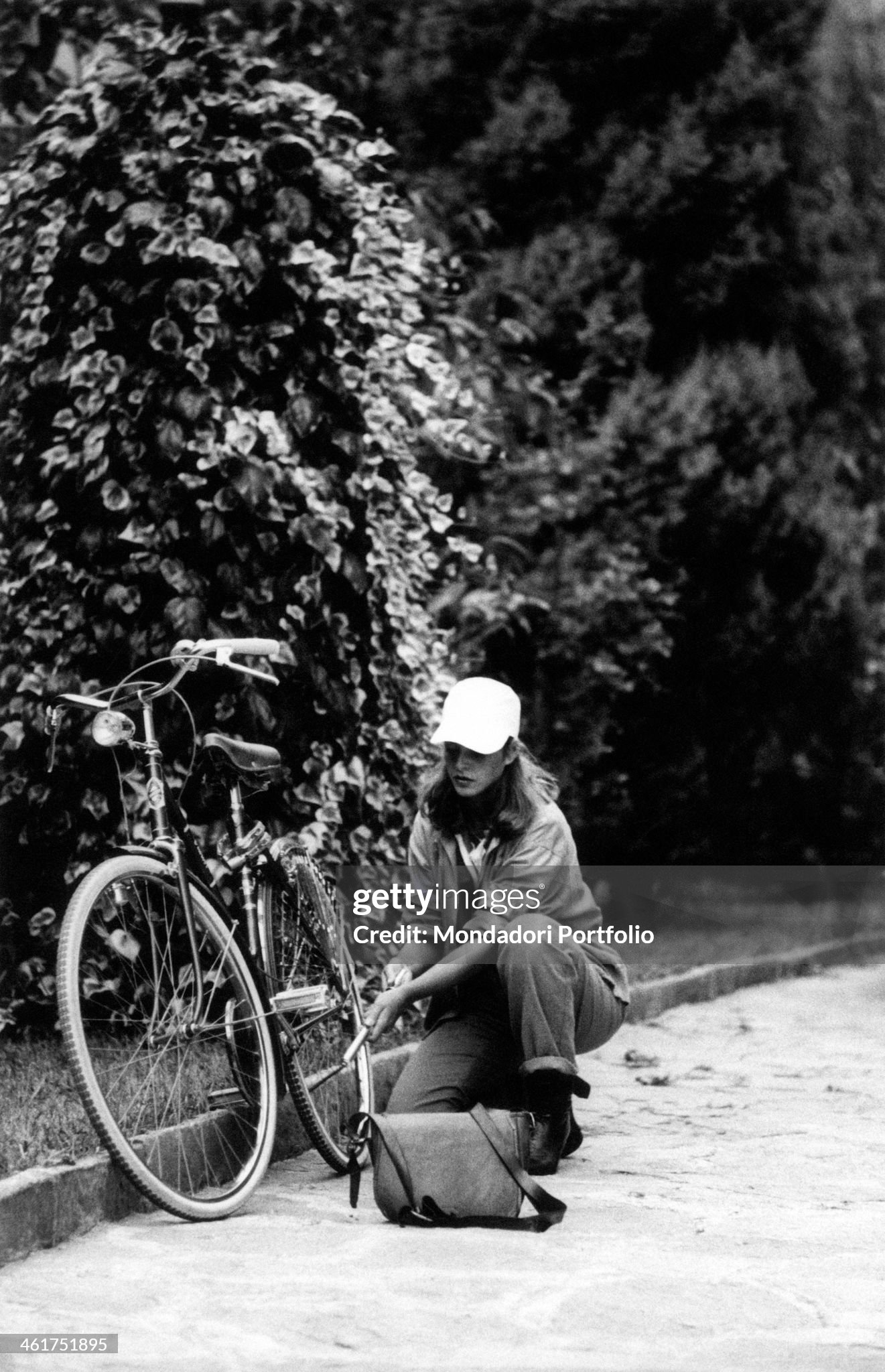 A young woman inflating the rear wheel of her bicycle in Milan in 1970s. 