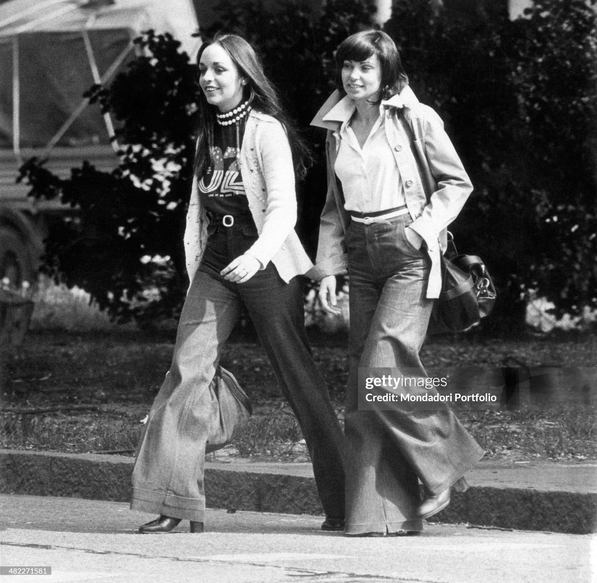 Two girls in jeans crossing the street in Milan in 1973. 