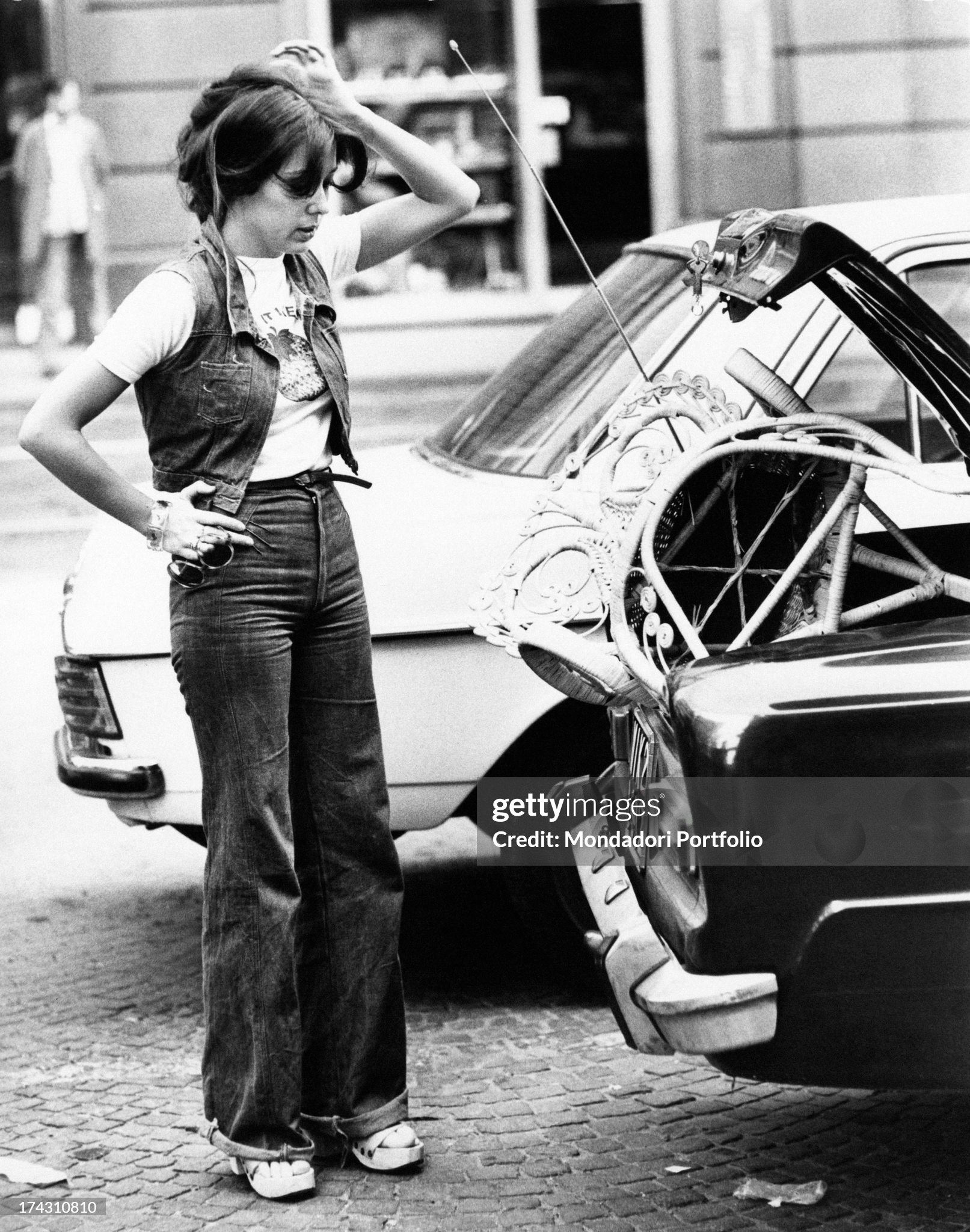 Italian showgirl Sabina Ciuffini trying to put a chair in the boot of her car in Milan in 1975. 