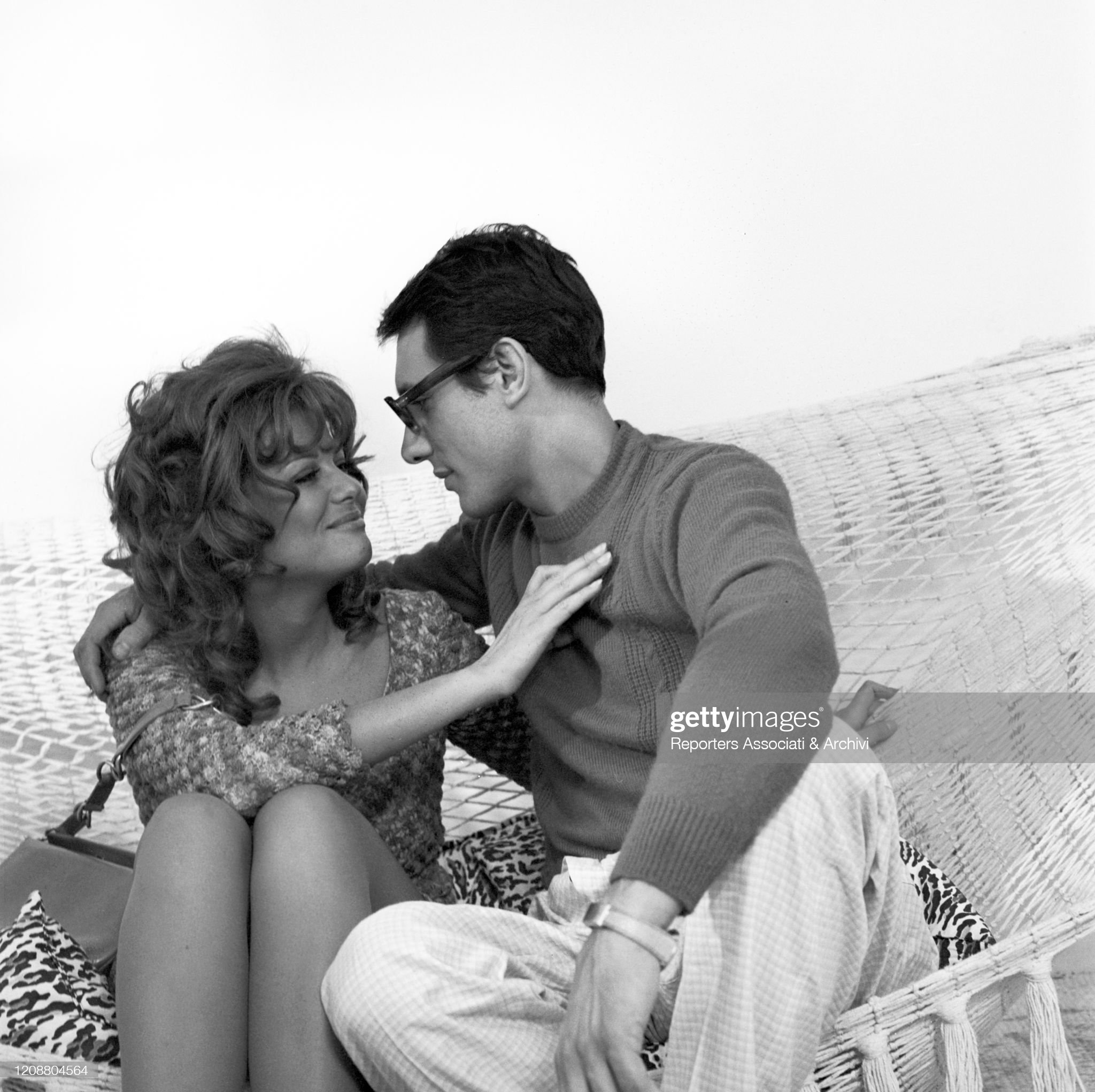 Italian actress Claudia Cardinale (Claude Joséphine Rose Cardinale) and Enzo Jannacci hugging each other sitting on a hammock in the film ‘Papal Audience’ in Italy in 1972. 