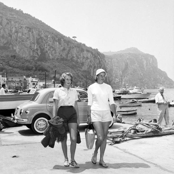 Swedish born screen star Ingrid Bergman and her daughter Pia Lindstrom, both wearing shorts in typical Capri-like fashion, walk together along the waterfront during their vacation on the Honeymoon Isle in 1957. 