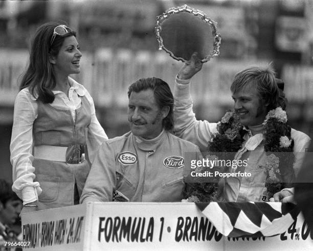 Ronnie Peterson holds up his trophy as he stands with Britain's Graham Hill after winning the 40 laps Rothmans International race at Brands Hatch, England, on 30 August 1971. 