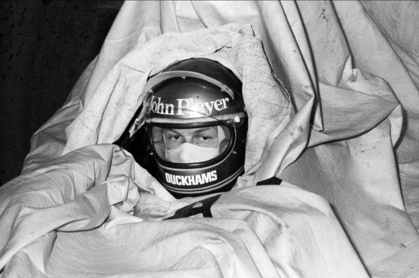 Ronnie Peterson who crashed out of the race on lap 3 in a troubled race meeting for the new Lotus 76, keeps himself well covered during a rain storm at the South African Grand Prix in Kyalami, South Africa, on 30 March 1974.