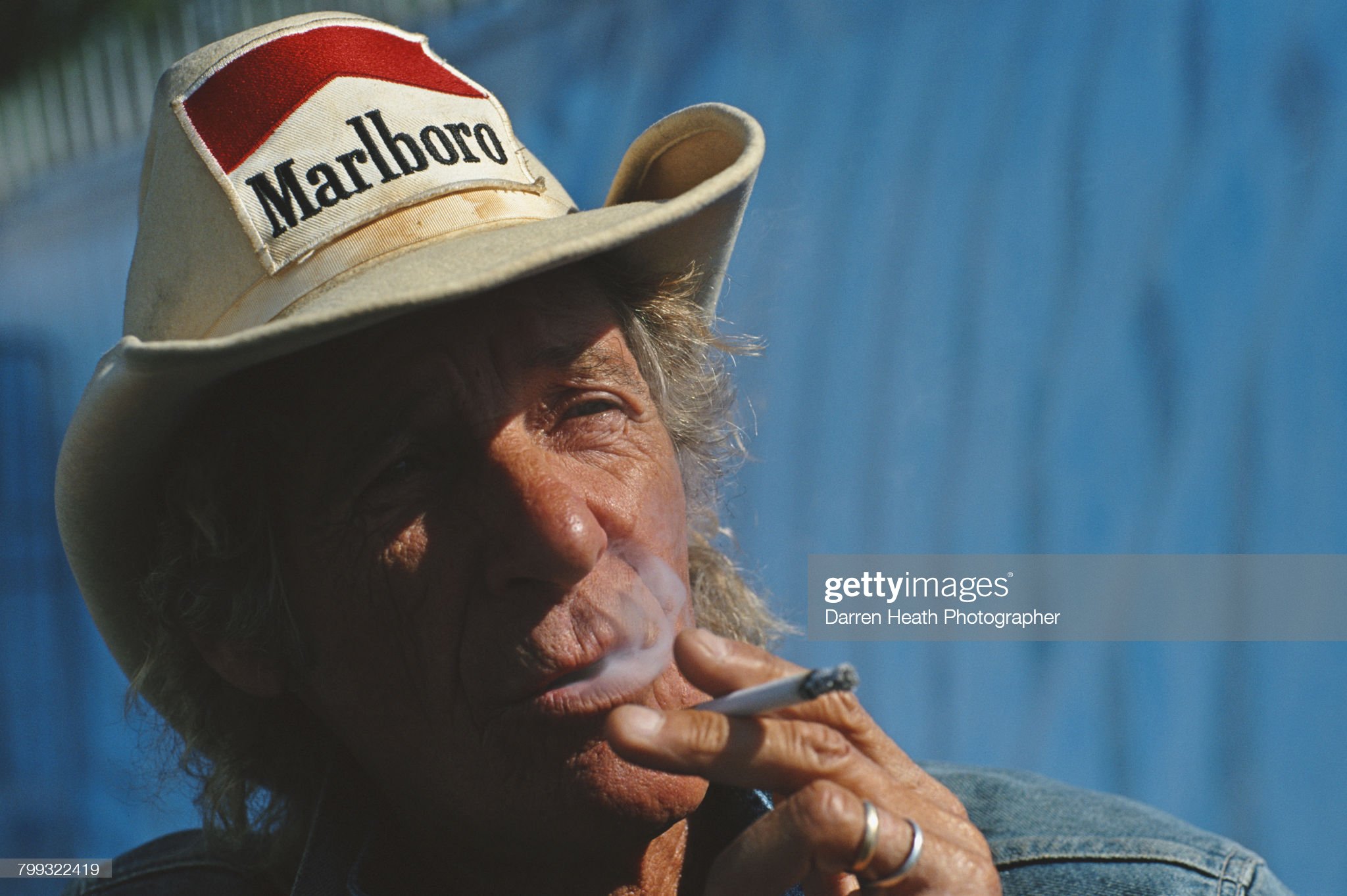 Arturo Merzario smokes a cigarette whilst wearing his trademark Stetson cowboy hat with sponsorship patches from Marlboro during the Formula One Italian Grand Prix on 16 September 2001 at Monza. 
