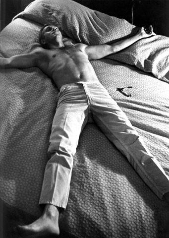 Steve McQueen lying on a bed.