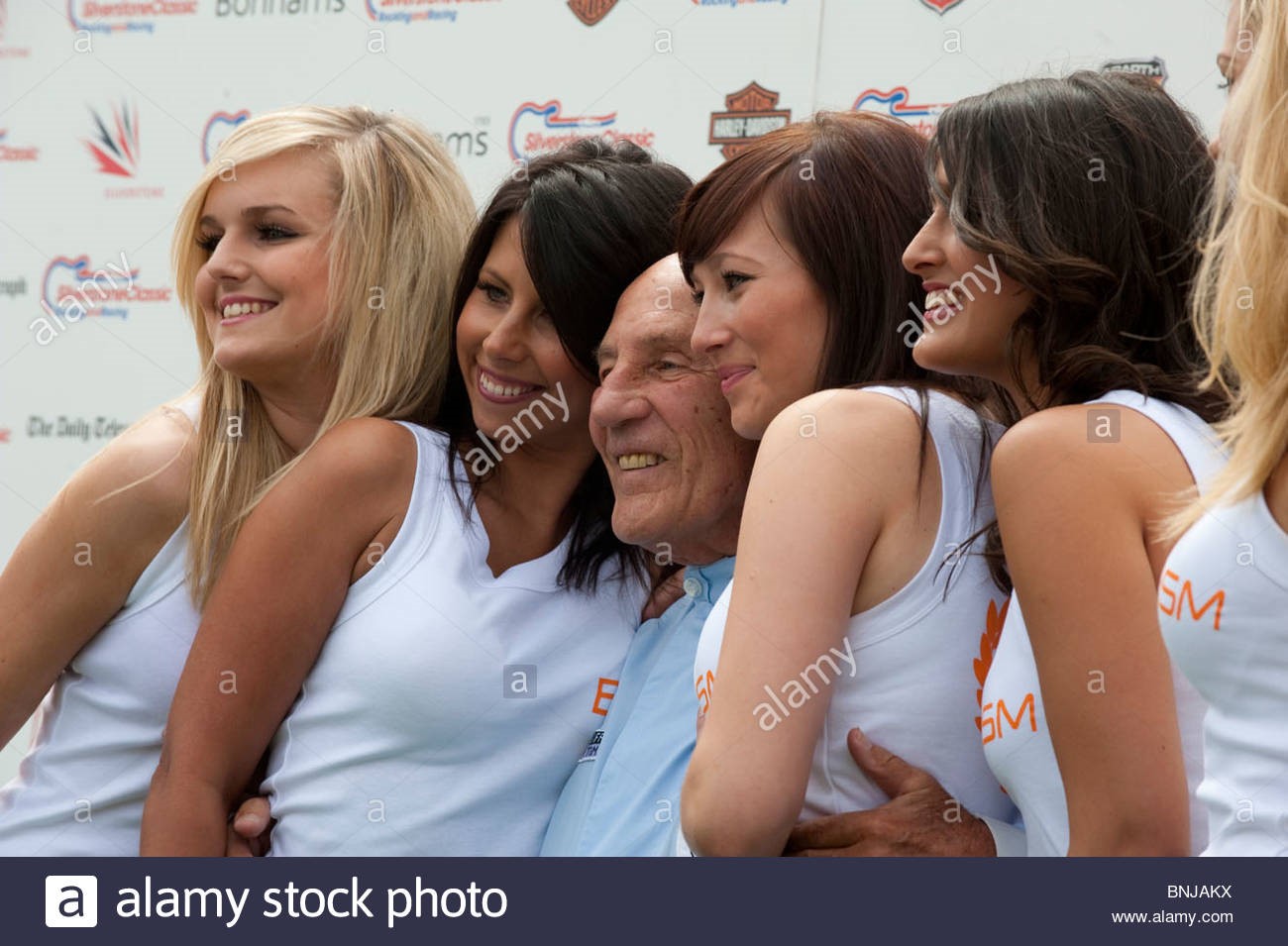 Sir Stirling Moss with promotions girls at Silverstone.