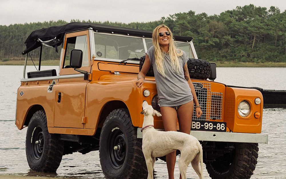 A girl with a dog and an orange Land Rover.