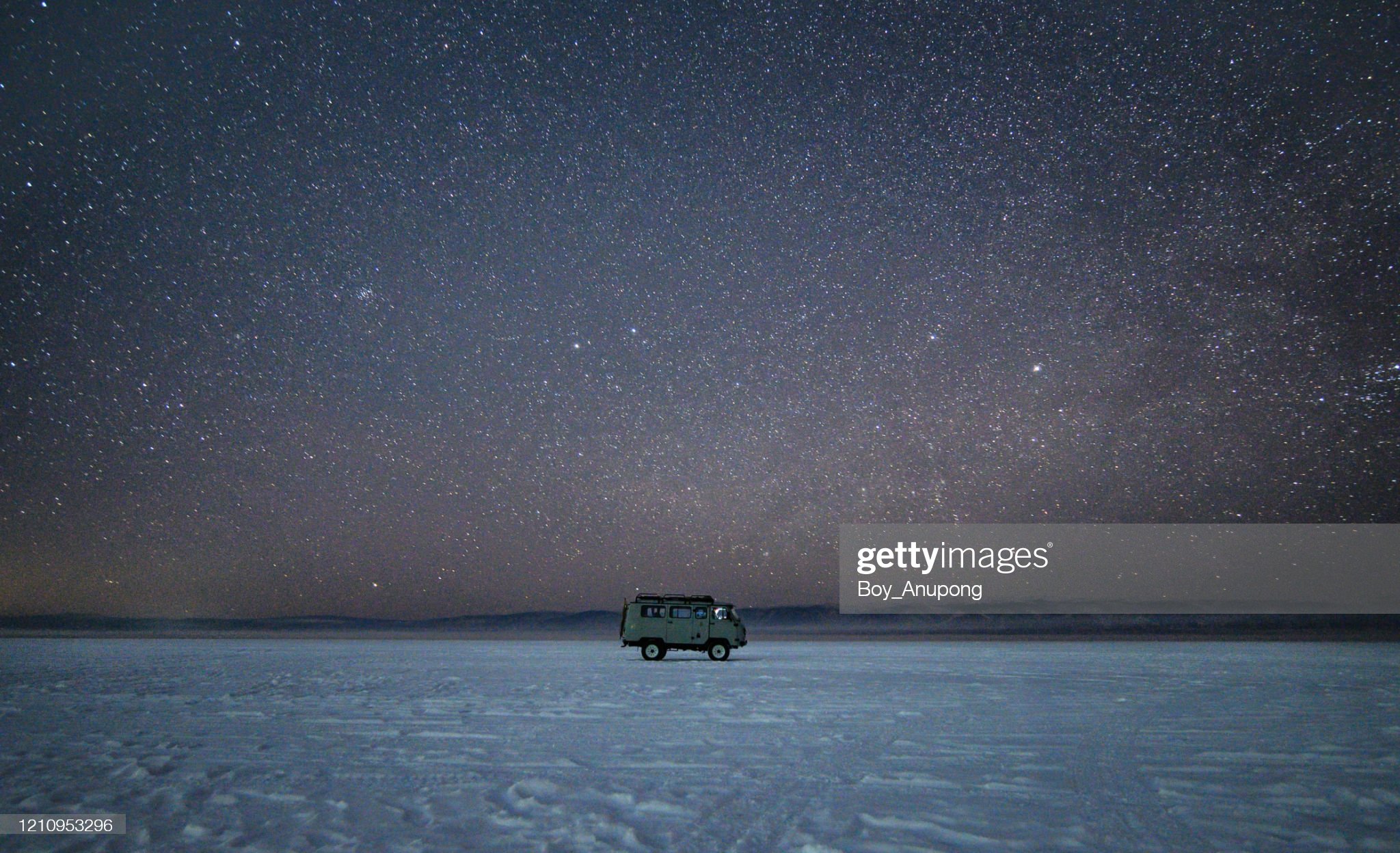 The Russian UAZ van parking on frozen lake Baikal, Russia, under the stars in starry night.