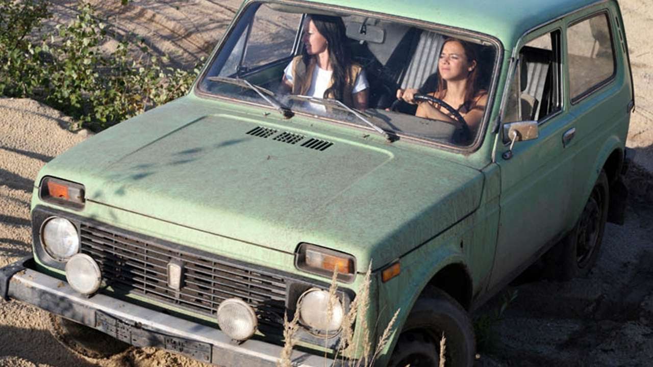 Two girls in a green Lada Niva.