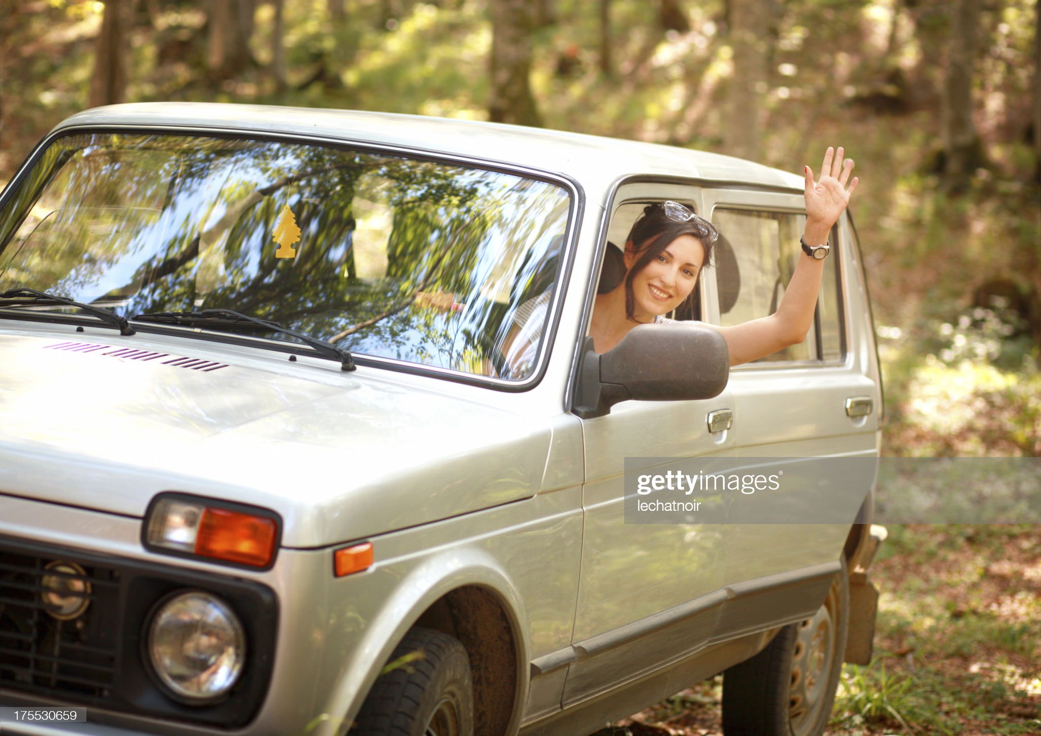 Woman driver in the nature waving a hand.