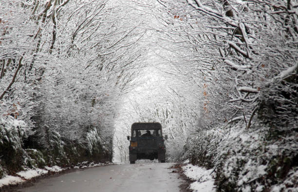 A Land Rover drives down a road with a line of snow covered trees near Dulverton on January 30, 2012 on Exmoor, England.