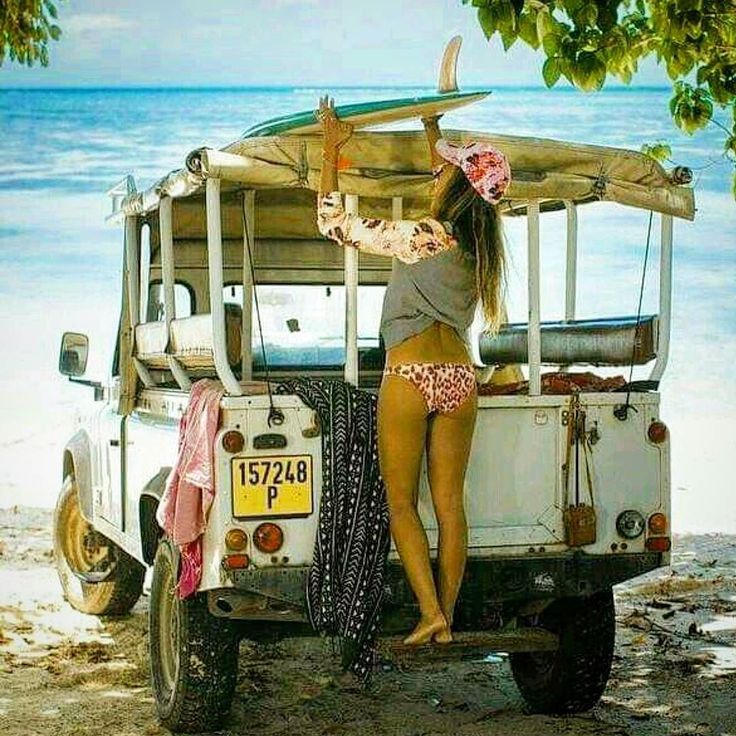 A girl with a surf and a Land Rover.