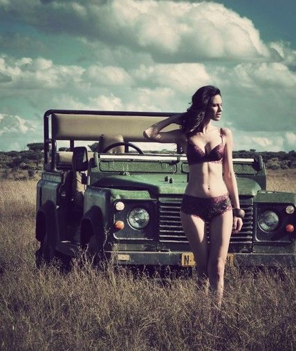 A girl in bikini in front of a green Land Rover.
