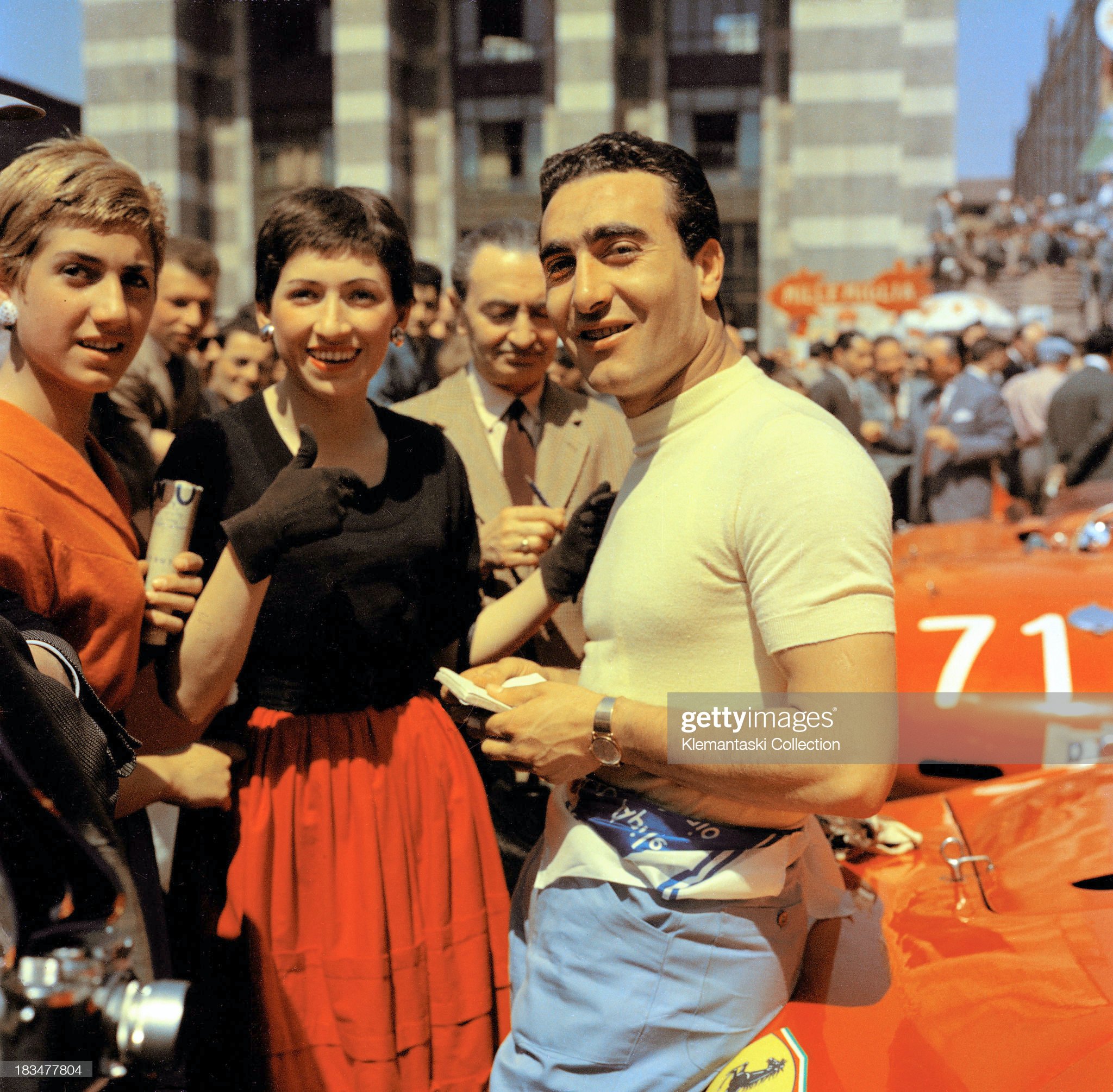 Ferrari team leader Eugenio Castellotti chats with two ladies.