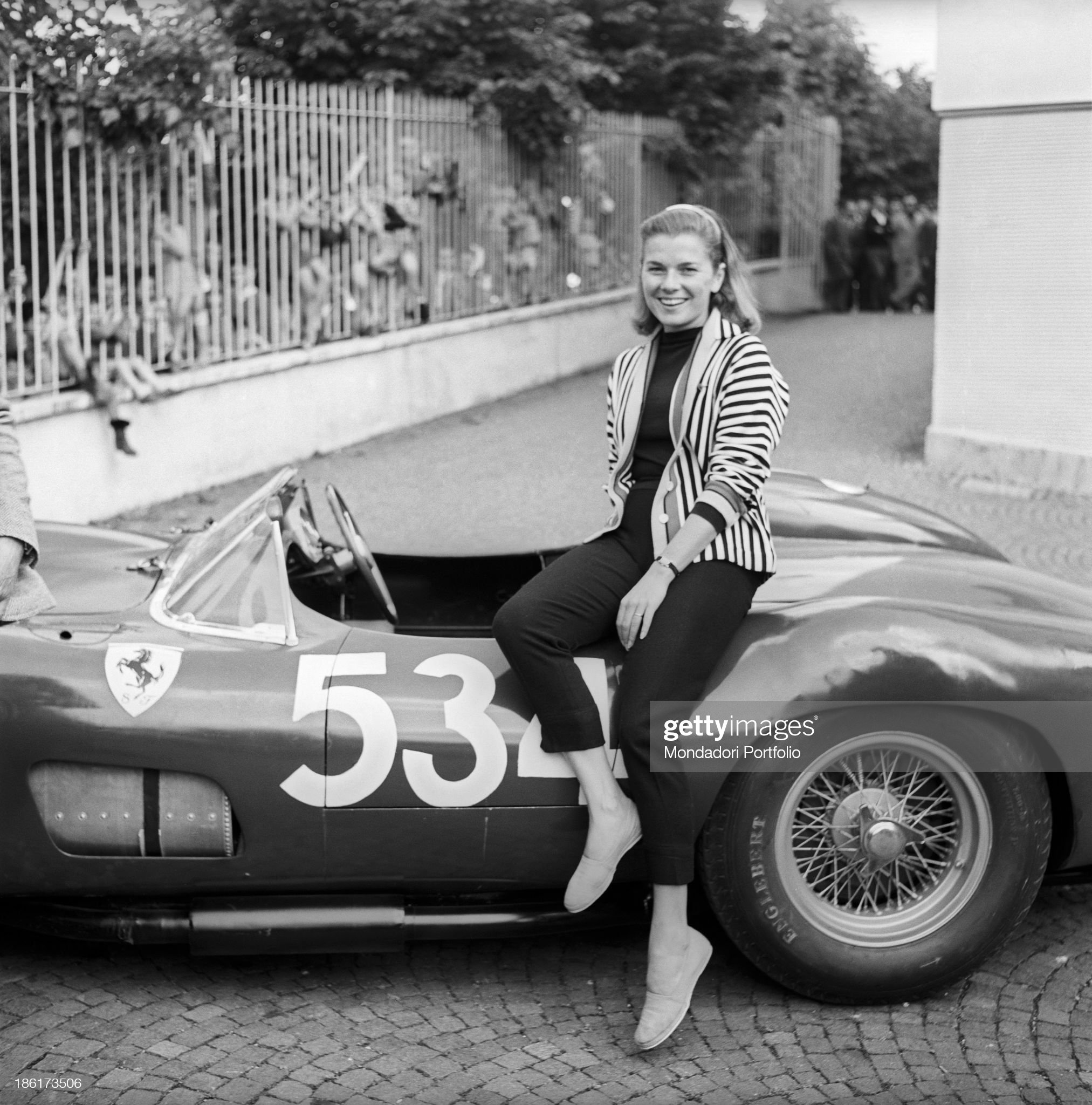 Louise Collins posing smiling at the wheel of the car driven by her husband and British racing driver Peter Collins at the Mille Miglia Automobile Race. Italy, May 1957. 