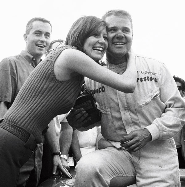 Mark Donohue is congratulated for his victory in the 1966 Nassau Trophy race as Roger Penske looks on.