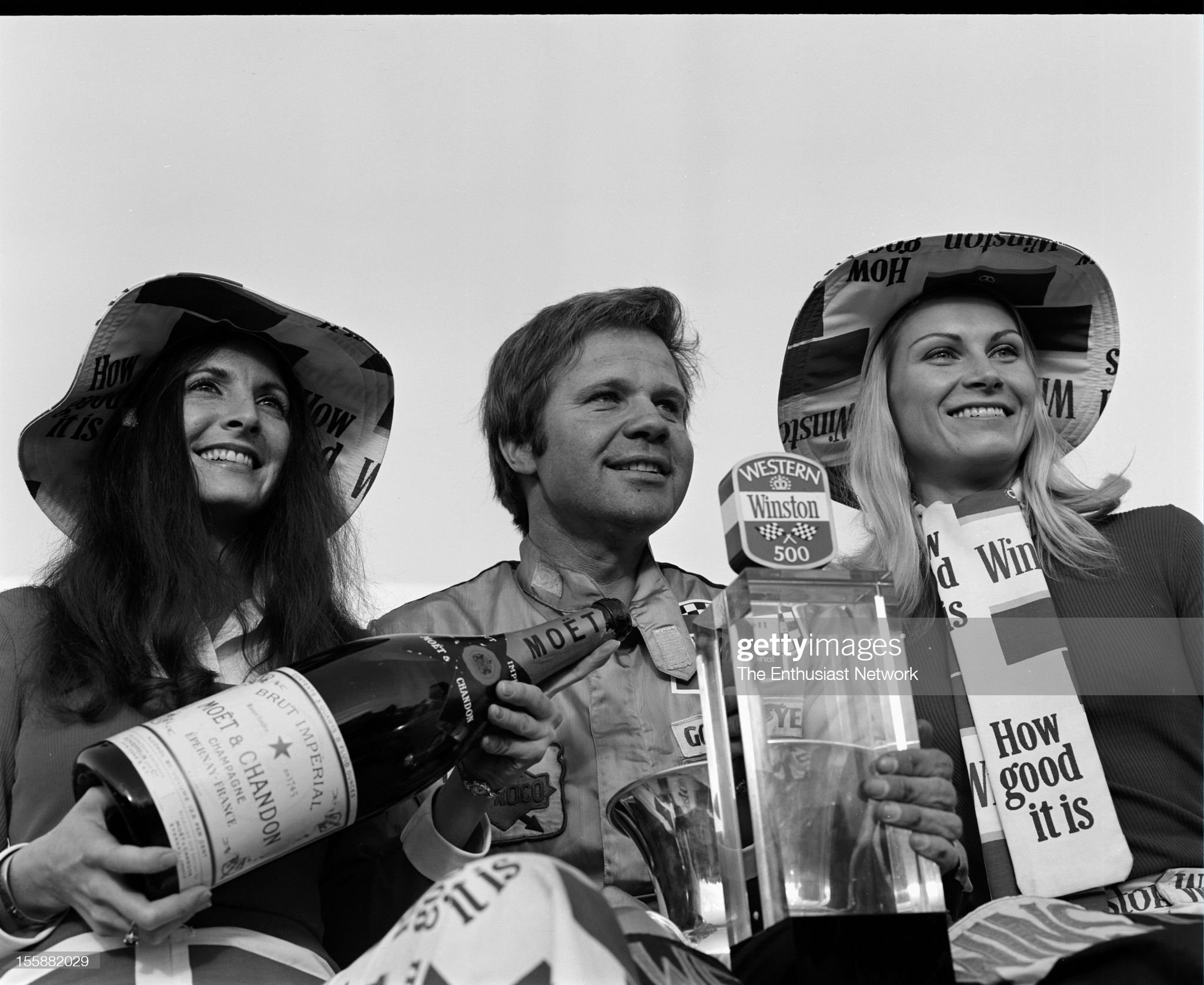 Mark Donohue celebrates with the Winston Western grid girls, holding the first place trophy.