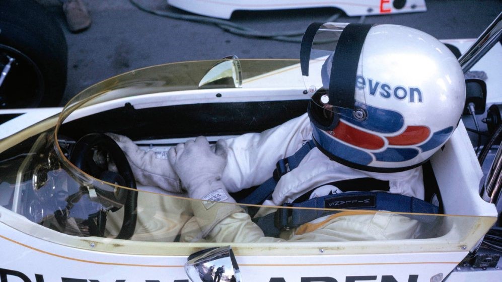 Revson shows off his iconic helmet design as he sits in his McLaren.