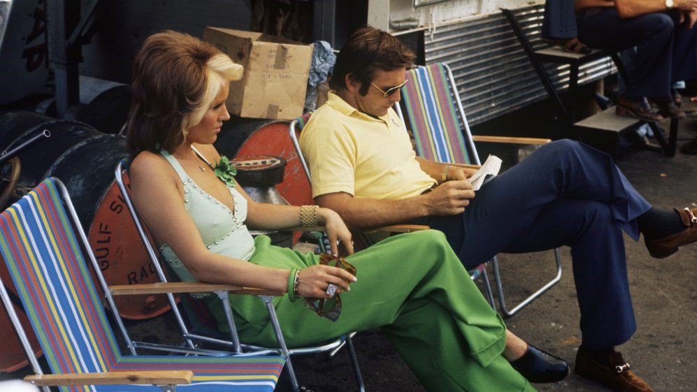 Peter Revson, McLaren, relaxes with a book alongside a female companion.