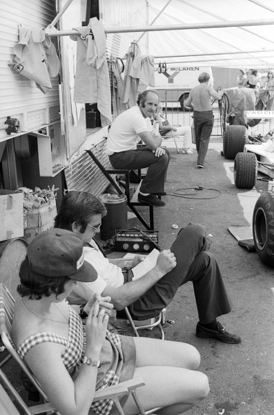 Peter Revson, McLaren, (nearest) reads a book in the paddock as eighth placed team mate Denny Hulme (background) sits and reflects. 