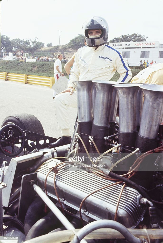 United States, October 20, 1970, Monterey, Castrol Grand Prix, Laguna Seca, Can-Am. Pedro Rodriguez stands with his helmet on next to his BRM P154's bare chassis in the pits.