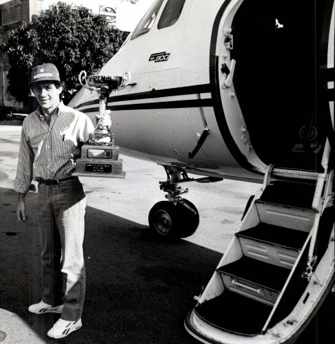Ayrton Senna with a trophy in front of his private plane.