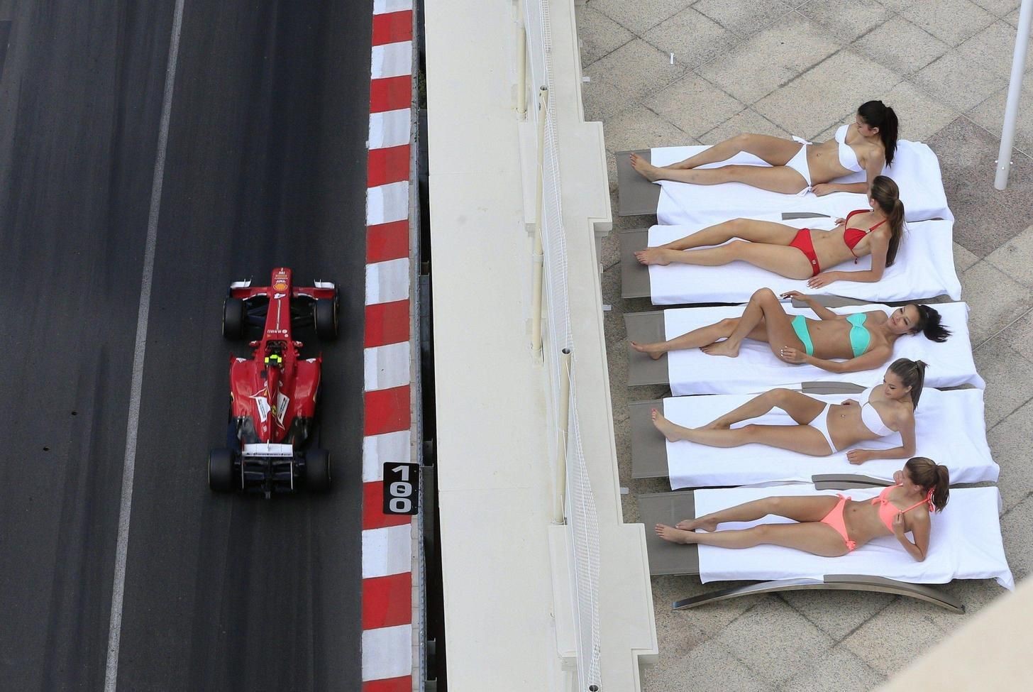 Women top up their tans as Felipe Massa races past. 