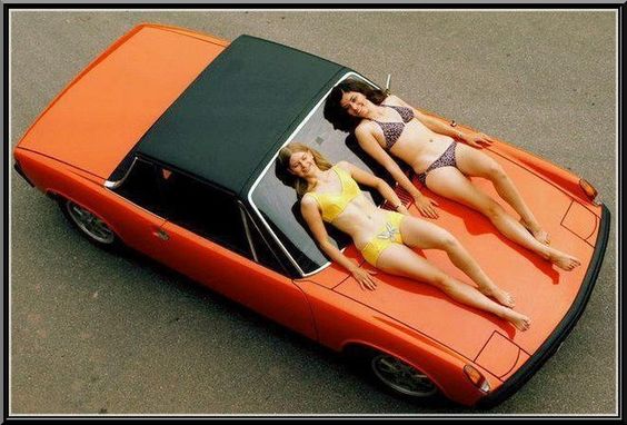 Two girls in a bikini on an orange Porsche 914.