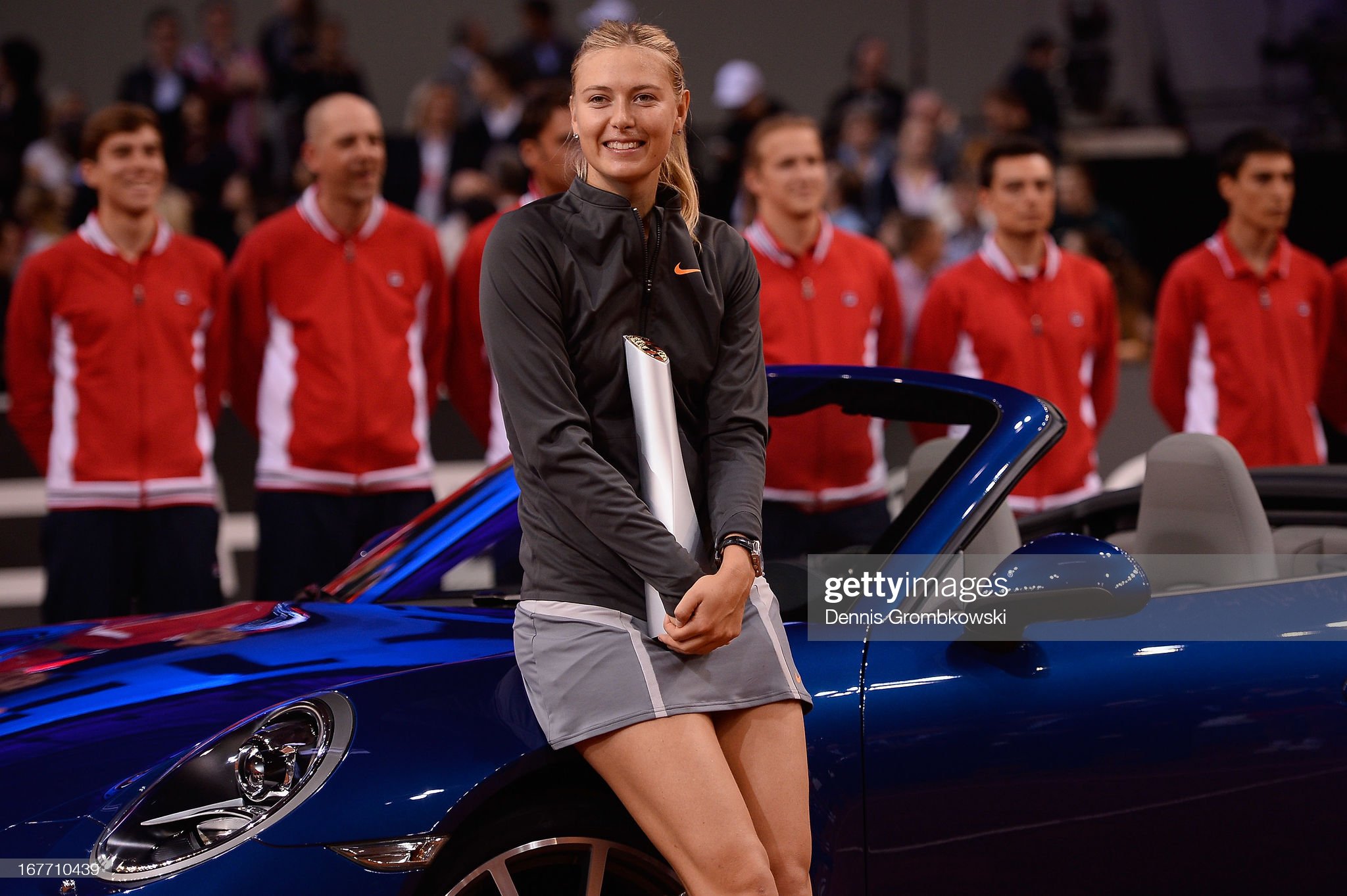 Maria Sharapova poses with her trophy and a blue Porsche 911 Carrera 4S Cabriolet.