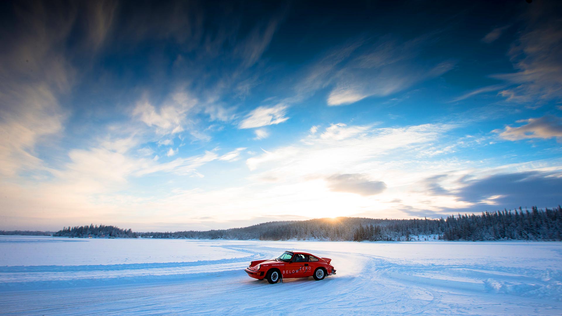 A red Porsche driven on the snow.