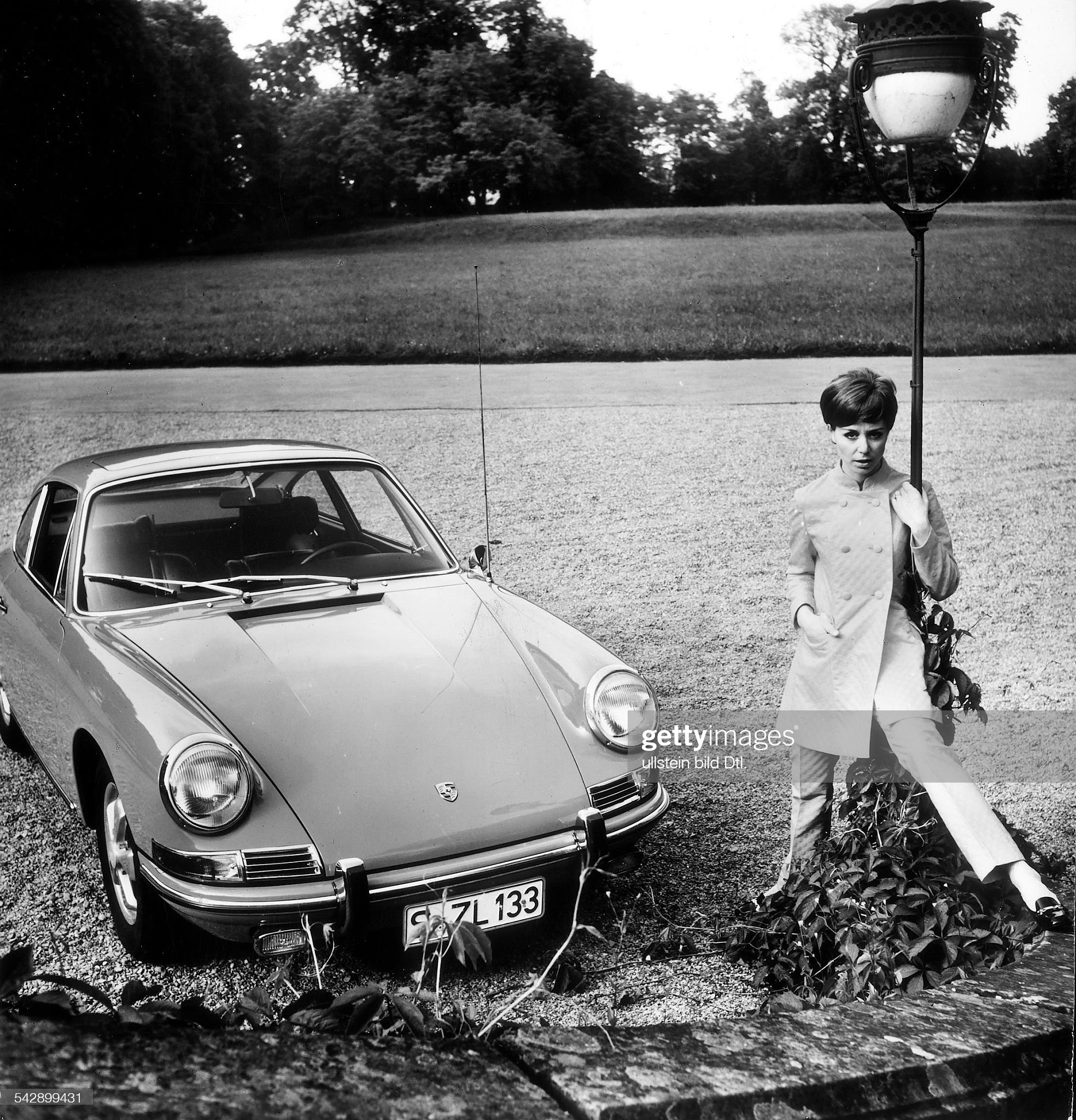 A young woman stands next to a Porsche model 911/912, probably from the mid-1960s. 