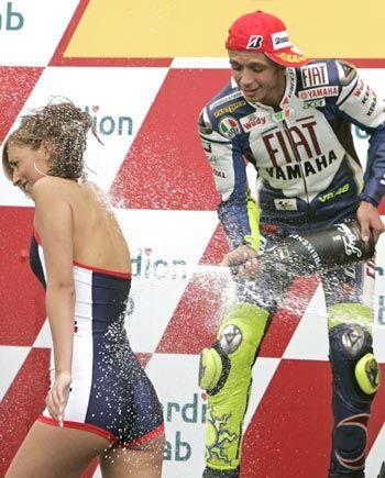 Valentino Rossi spraying champagne from the podium on a girl.