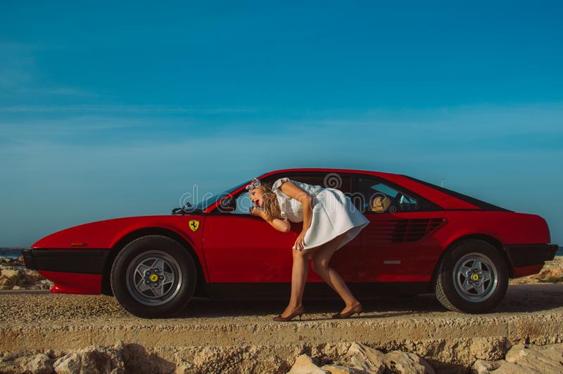 16 October 2016, Maghtab, Malta. A young girl does makeup in the rear view mirror of a Ferrari, at the seaside.