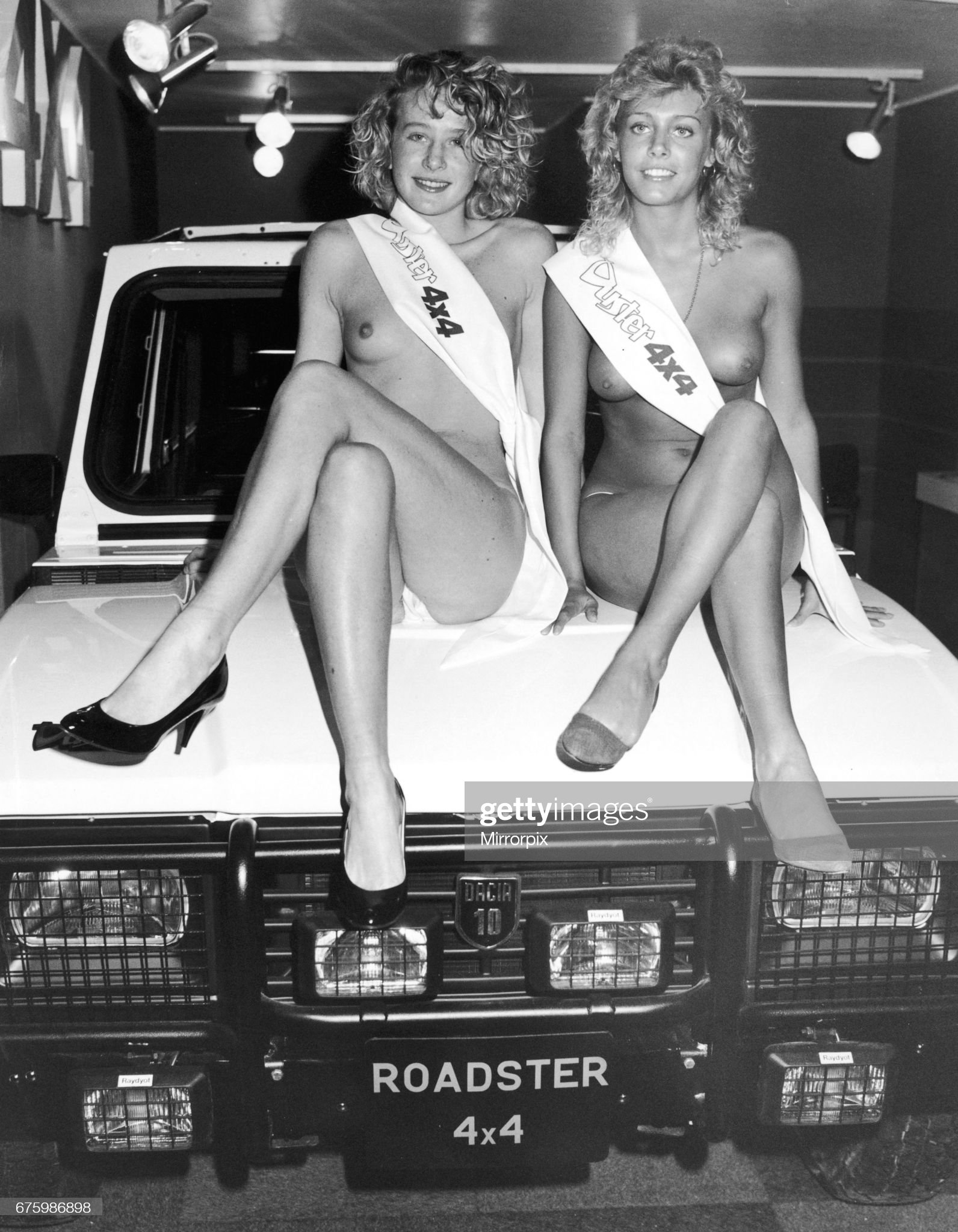 Two topless models sit on the bonnet of the Dacia 10 Roadster 4x4 at the 1984 Motor Show on 17 October 1984.