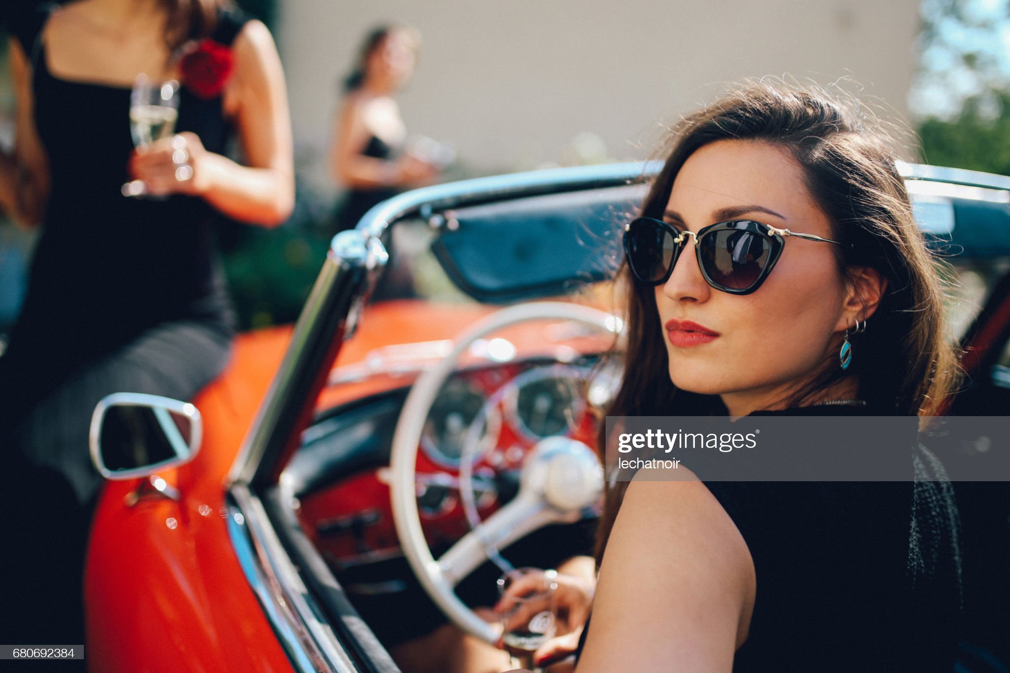 Young fashionable girl in an oldtimer convertible sportscar.