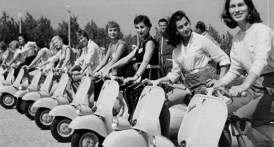 Snapshot, 1955: ladies, start your engines. 16 July 2017. It’s summer 1955, and there’s no better time for a ride. The obvious choice of vehicle on this warm, sunny day is the perpetually entertaining Vespa. But if you’re looking to get on one soon, you’ll need to act fast, as they’re being snatched up rather quickly… There’s no other quintessential summer ‘ride’ than a Vespa. With its peppy little motor, open-air driving and the perfect seat for two, it screams free, uninhibited holiday fun. And after seeing Audrey Hepburn cosy up to Gregory Peck on one in Roman Holiday, every holidaymaker wants to try it out for themselves. Who knows, maybe it’ll take them on a romantic holiday adventure of their own? 