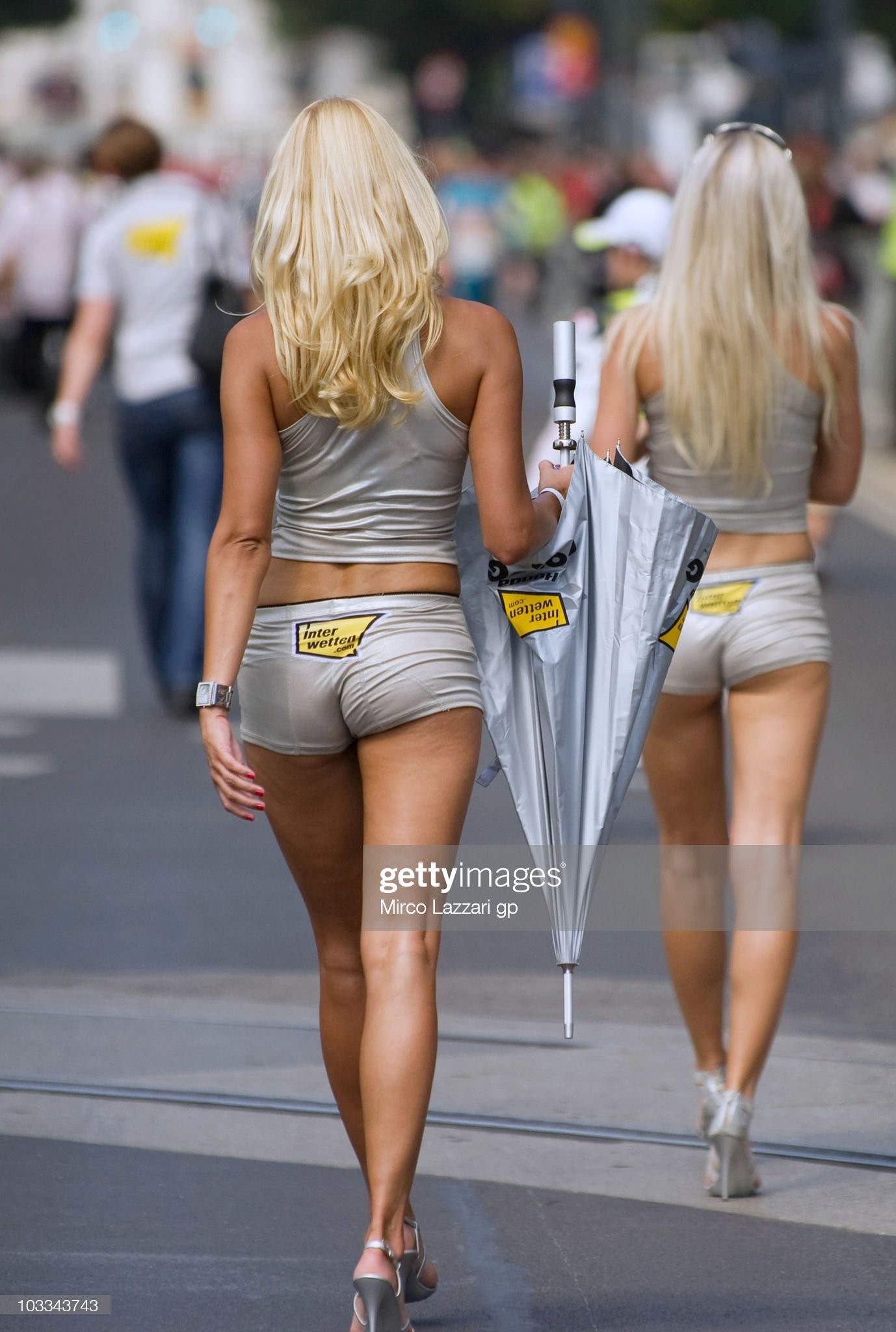 Grid girls from Interwetten MotoGP Team walk in front of fans during the pre-event 