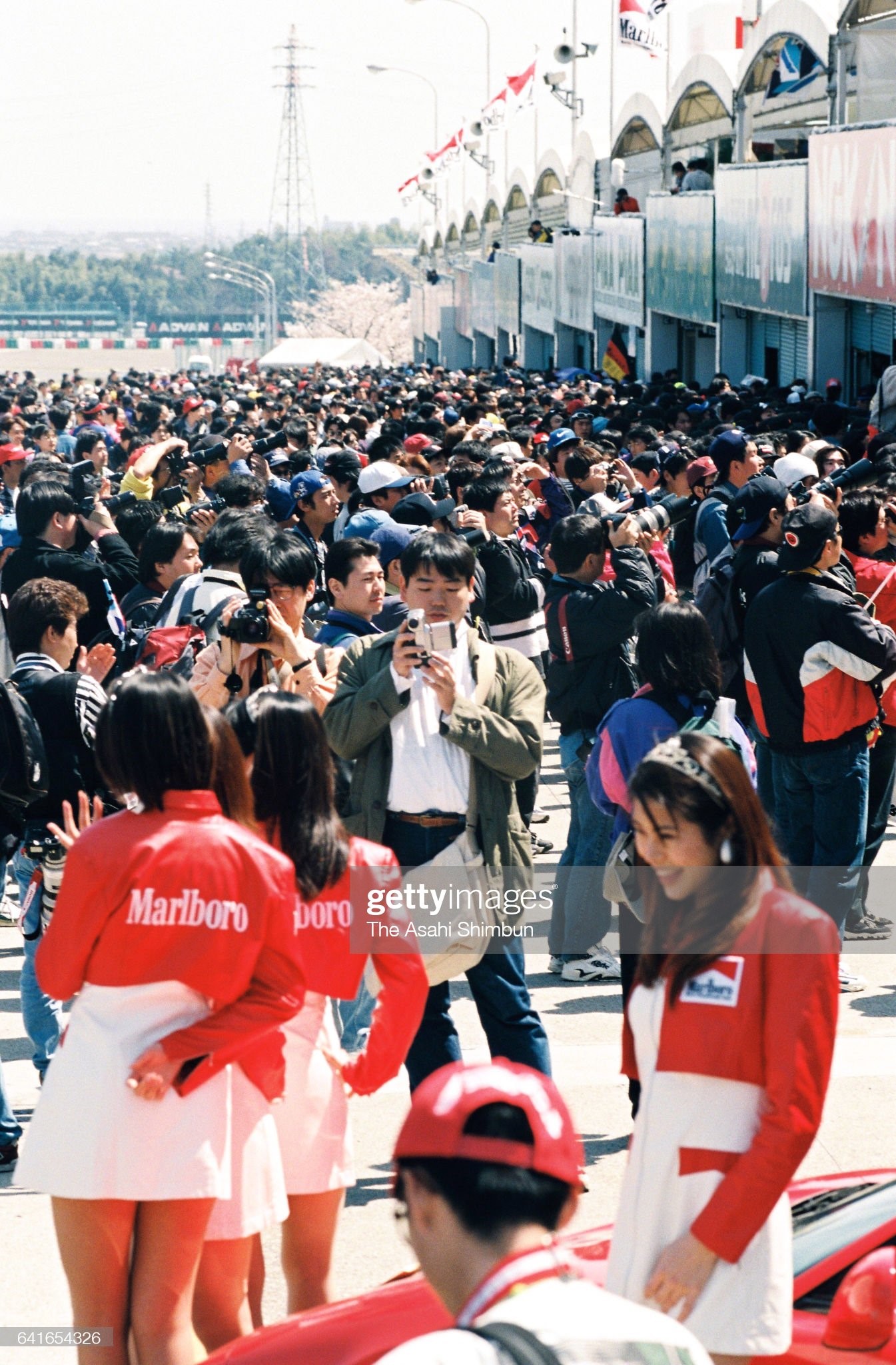 Grid girls wave to fans in a paddock during the qualifying of the Motorcycle Japan Grand Prix at Suzuka Circuit on April 04, 1998 in Suzuka, Mie, Japan. 