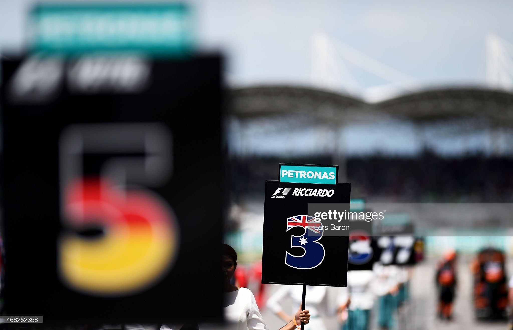 A grid girl poses with Daniel Ricciardo of Australia and Infiniti Red Bull Racing's number on the grid before the Malaysia Formula One Grand Prix at Sepang Circuit on March 29, 2015 in Kuala Lumpur, Malaysia. 