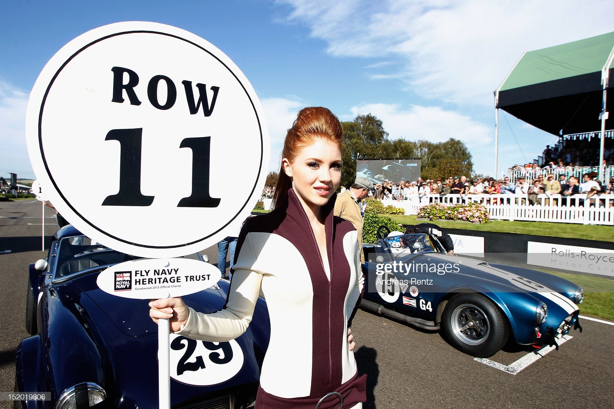 A grid girl stands next to Jochen Mass n.15 of Team Meilenwerk Historic Racing, during the Shelby Cup during the Goodwood Revival 2012 on September 15, 2012 in Chichester, United Kingdom. 
