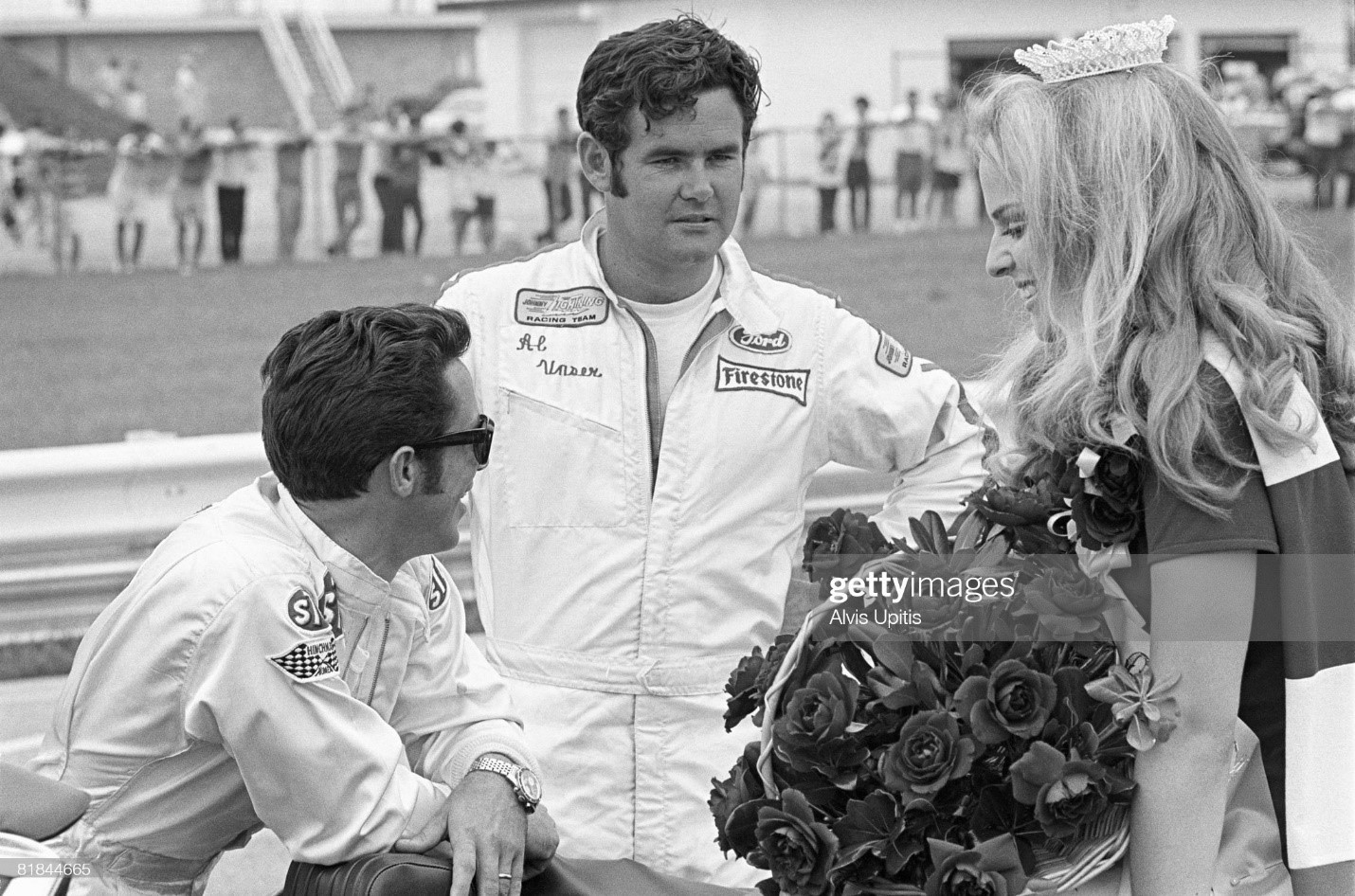 Mario Andretti (left) and Al Unser chat with the race queen before the start of the USAC INDY 150 Champ Car Race held on the road course at Indianapolis Raceway Park (IRP) on July 26, 1970 in Clermont, Indiana. 