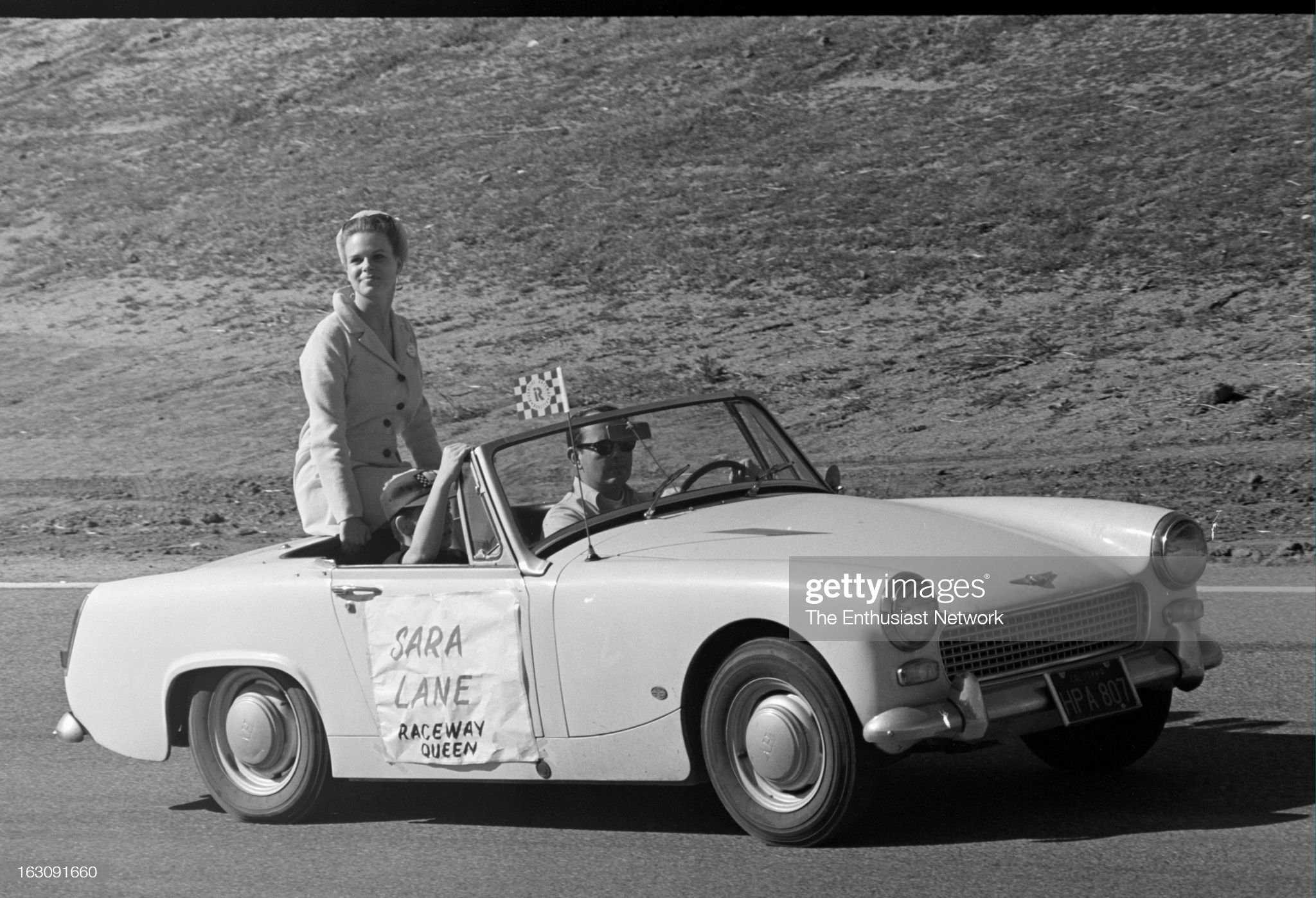 United States, January 22, 1968, Motor Trend 500, Riverside, NASCAR. Actress and Motor Trend 500 Race Queen Sara Lane goes around the track on a parade lap in the back of an Austin Healey Sprite. 