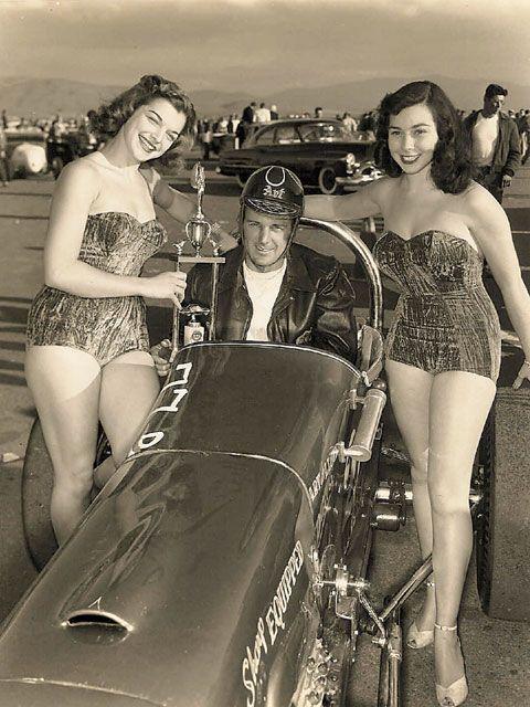 A vintage photo with a driver in his car and two girls.
