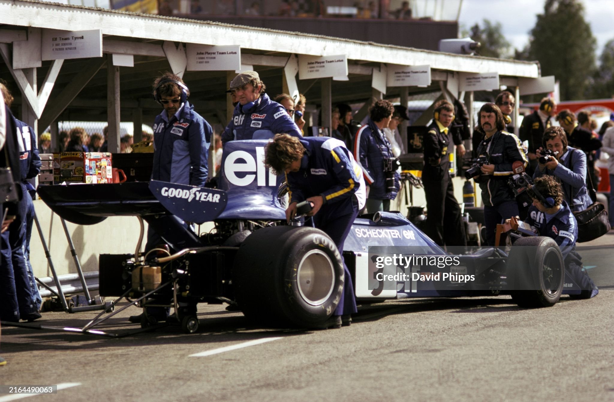 Jody Scheckter has checks made on his Tyrrell 007 in the pits during practice, as Tyrrell designer Derek Gardner (wearing flat cap) and Roger Hill, Tyrrell chief mechanic (headphones, sunglasses), ponder. 