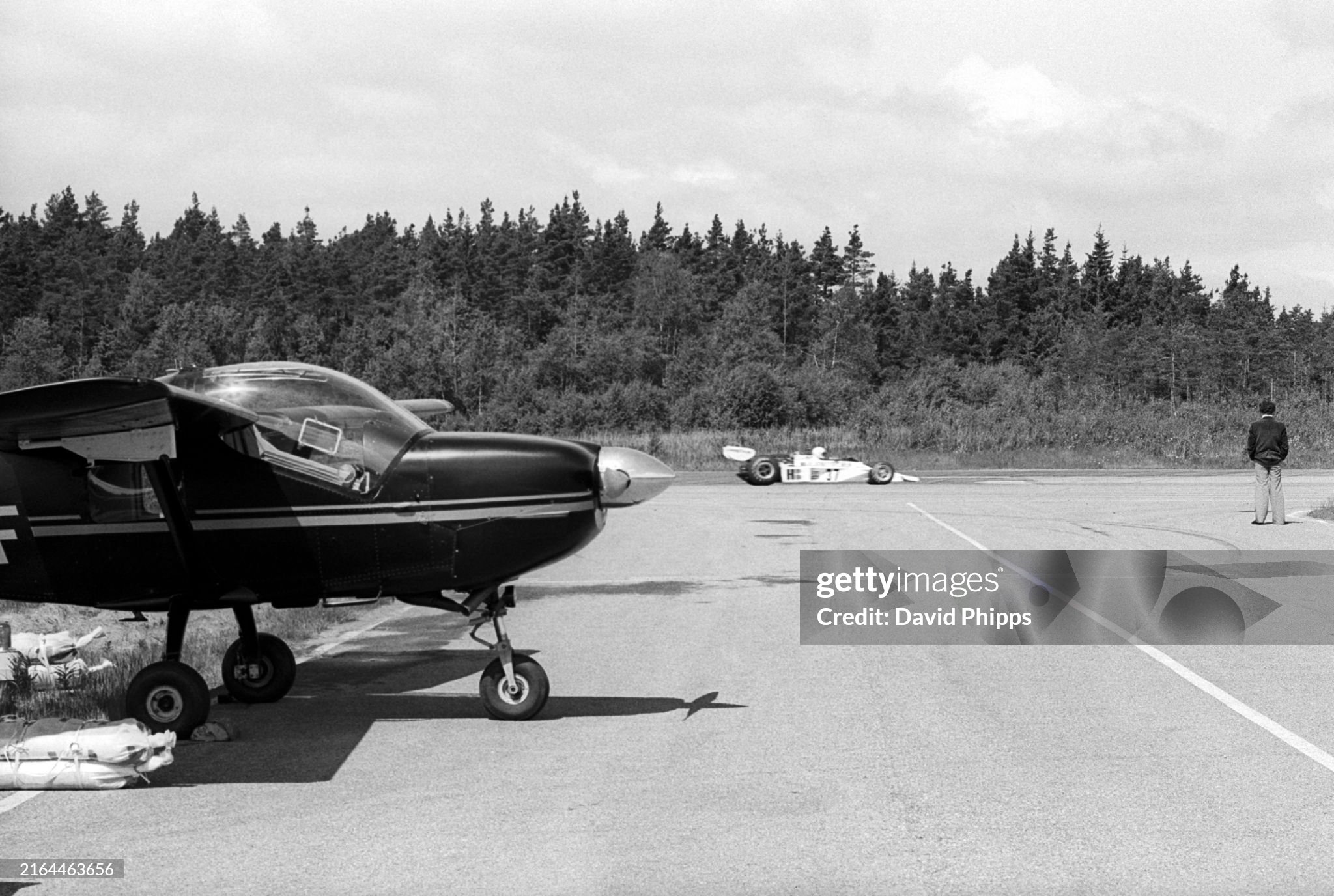 An F3 car passes a small aeroplane parked on the runway on the circuit infield at the Grand Prix of Sweden in Anderstorp on 13 June 1976. 